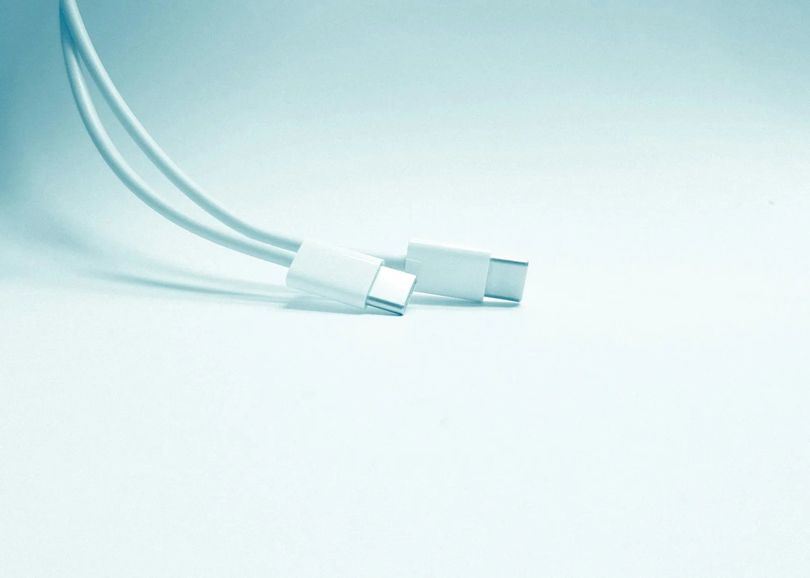 Cáp sạc USB-C đặt cạnh củ sạc và laptop trên bàn làm việc